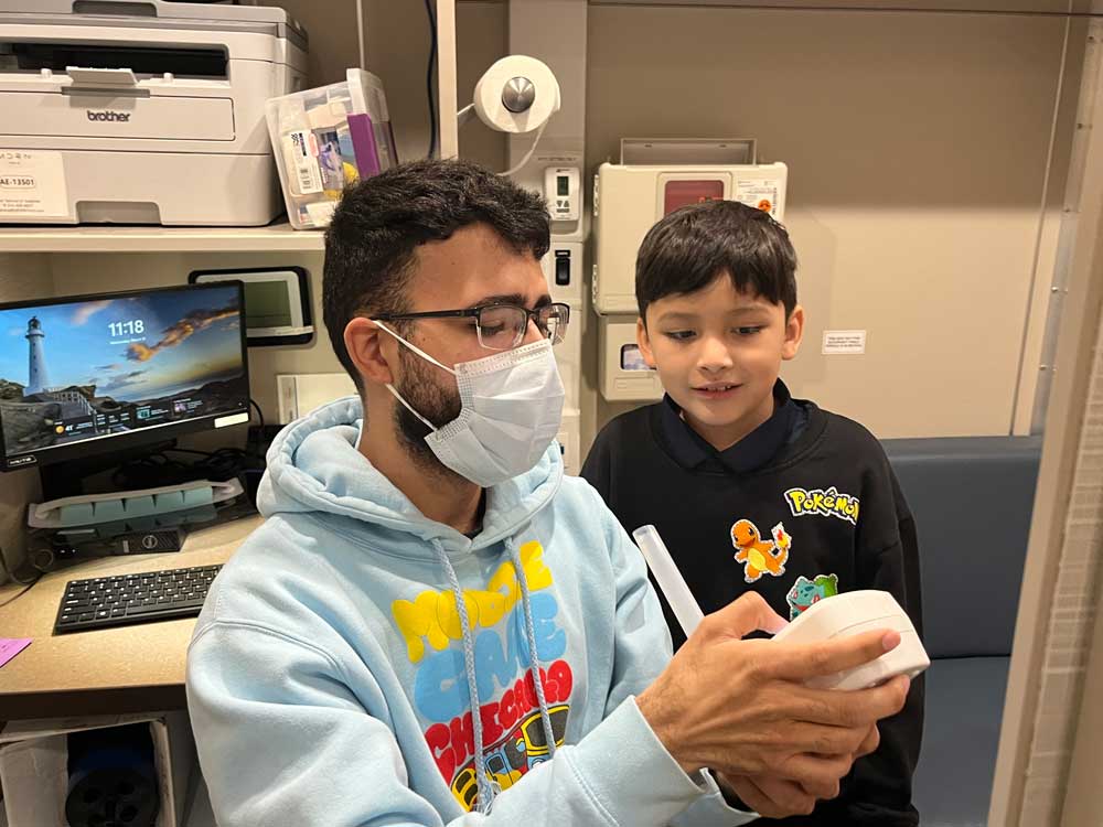 A Mobile Care Chicago team member demonstrates to a young patient how to use a FeNO analyzer.