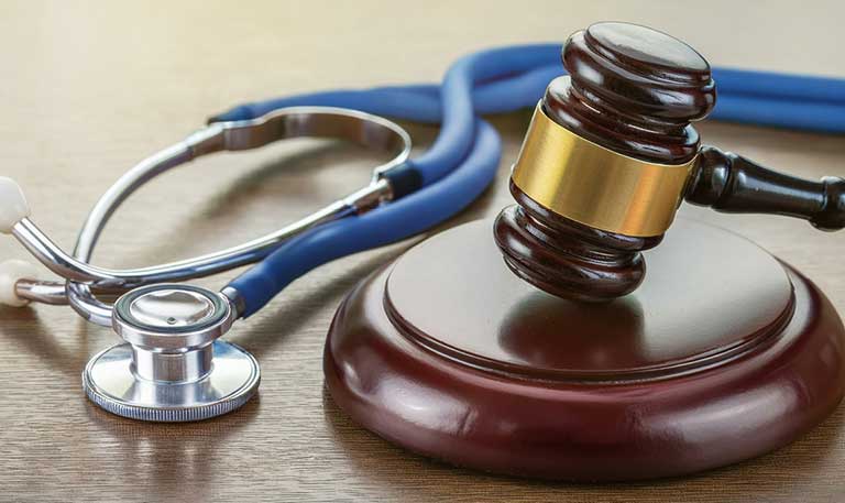 A stethoscope lays on a desk next to a gavel
