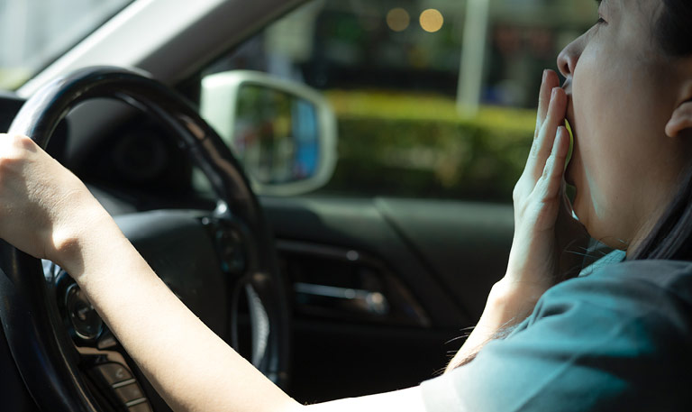Sleepy woman yawns while driving